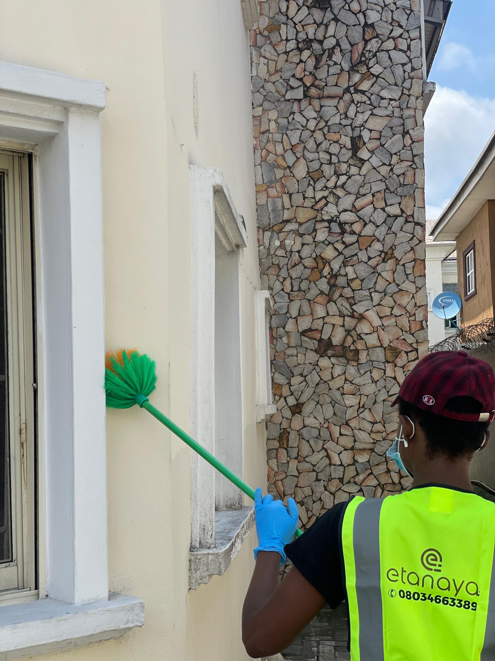Etanaya operative in branded hi-vis dusting exterior walls and window sills at a residential property