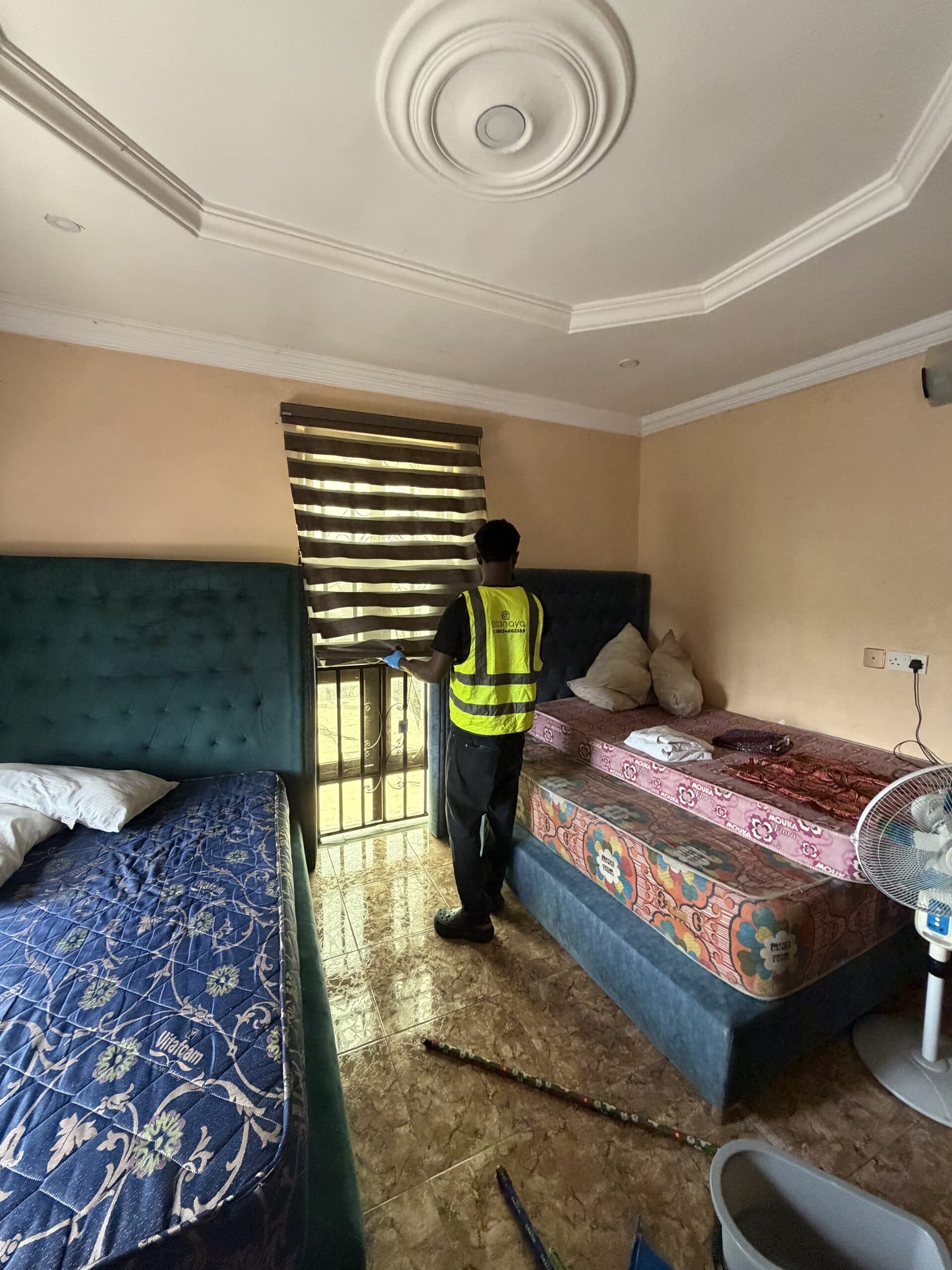 Etanaya operative in branded hi-vis cleaning a bedroom window during a residential deep clean