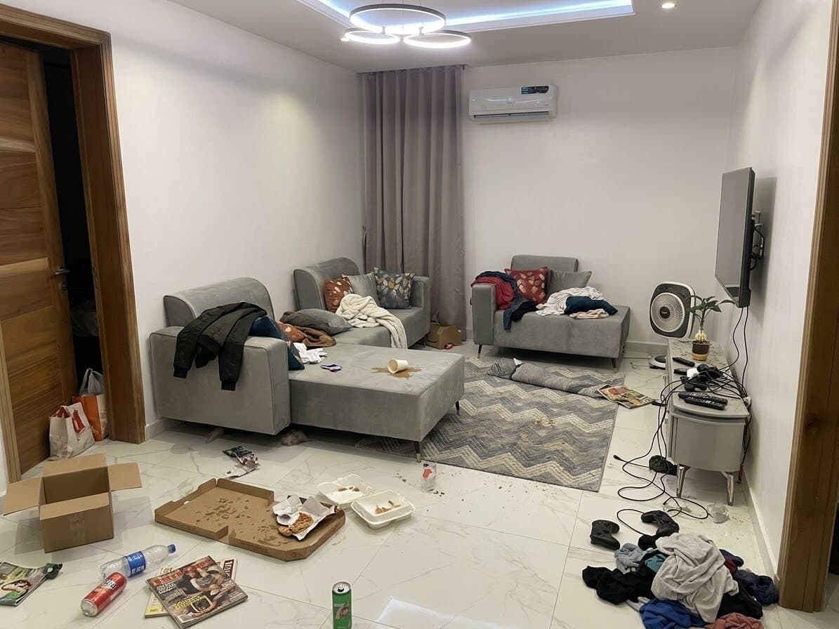Living room cluttered with boxes, clothes and food packaging before cleaning