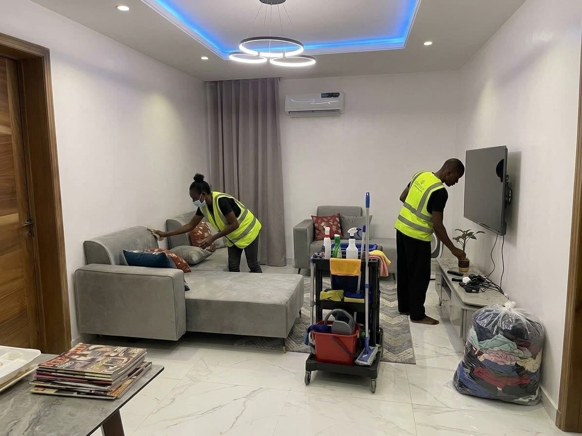 Two Etanaya operatives in hi-vis cleaning the living room with a kit trolley
