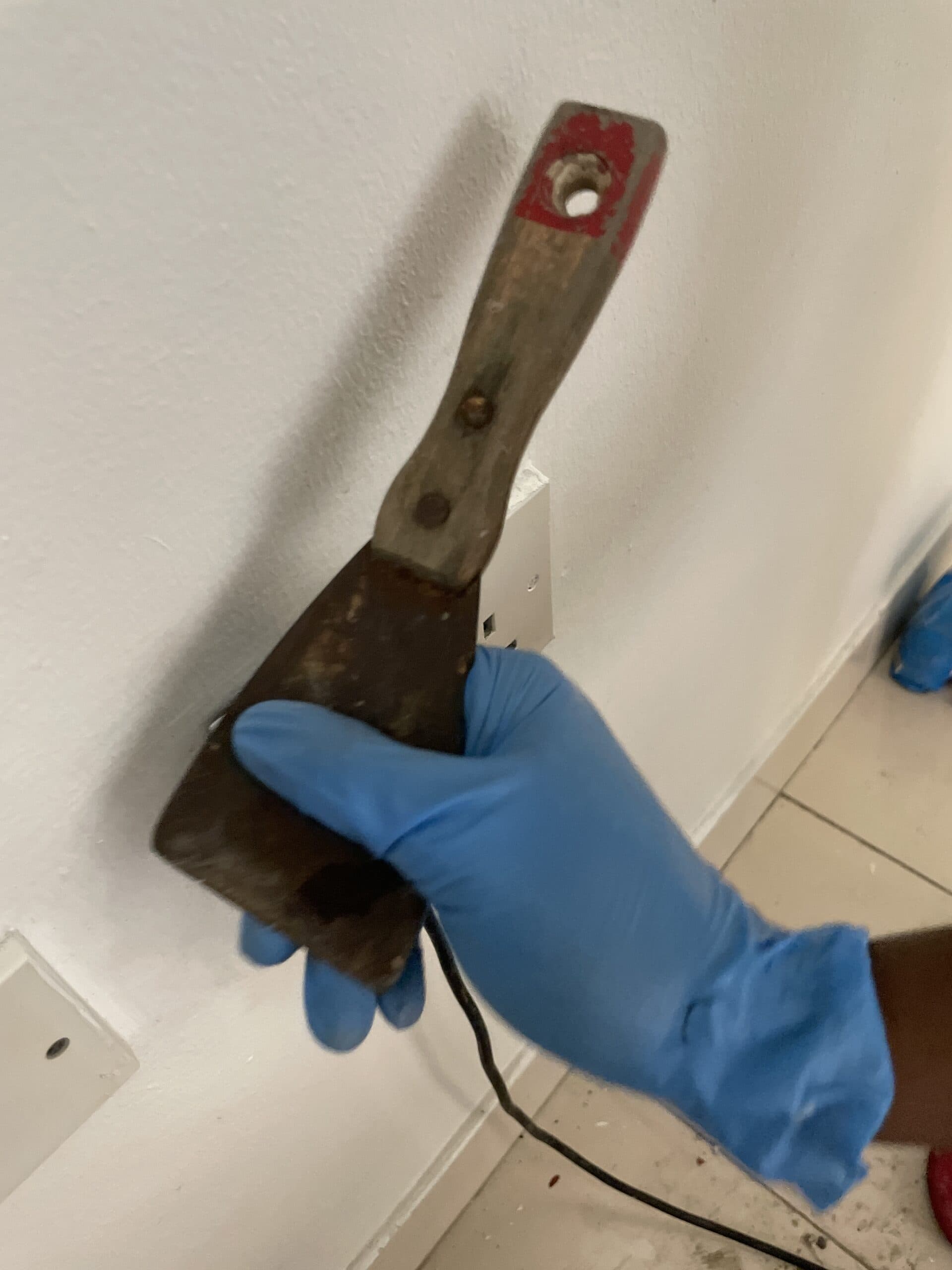 Gloved operative scraping hardened residue from the track